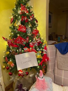 a decorated christmas tree in the corner of a living room with a sign that says merry christmas