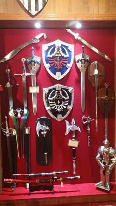 a display case filled with lots of different types of swords and shields on red wall