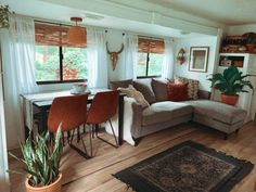 a living room filled with furniture next to a dining room table and window covered in curtains