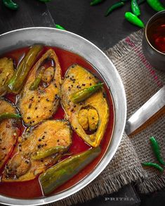 a pan filled with chicken and peppers next to a cup of tea on a table