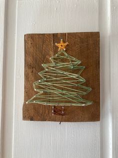 a christmas tree made out of wire on a wooden board with a star hanging from the top