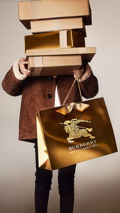 a man is holding several boxes on his head while wearing a brown coat and black boots