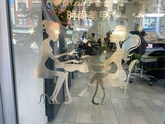 two mannequins are sitting at a table in front of a glass window