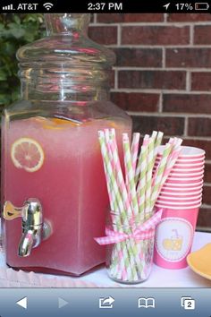 a beverage dispenser filled with pink lemonade and straws on a table