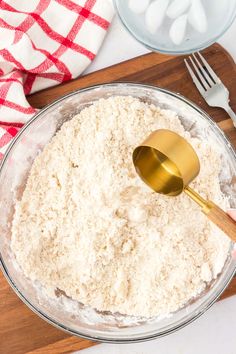 a wooden spoon in a glass bowl filled with flour