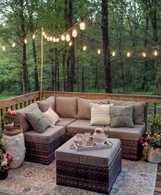 a couch and ottoman on a deck with string lights