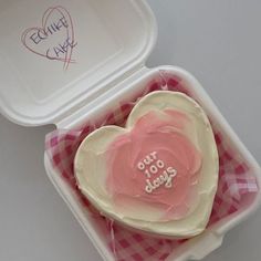 a heart shaped cake in a pink and white container with writing on the side that says our dog days