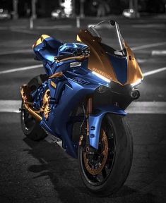 a blue and gold motorcycle parked in a parking lot next to a street at night