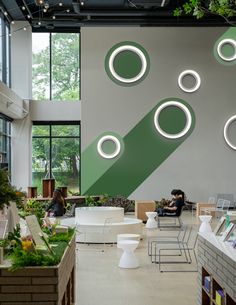 people are sitting at tables and chairs in a large room with circular lights hanging from the ceiling