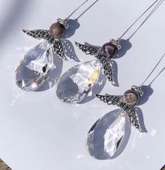 three crystal necklaces with angel wings hanging from them