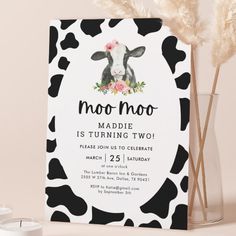 a black and white cow themed birthday party with flowers on it's head is shown in front of a card that says moo moo moo - moo