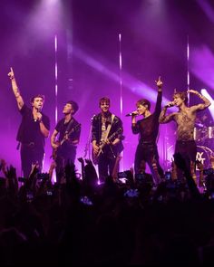 a group of people standing on top of a stage with microphones in front of them