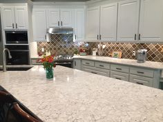 a large kitchen with white cabinets and marble counter tops, along with stainless steel appliances