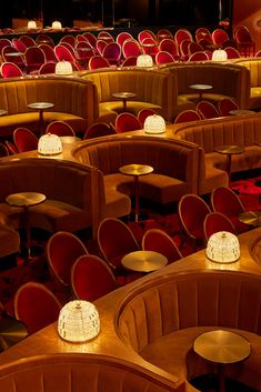 an empty auditorium with red velvet seats and round tables