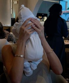 a woman holding a baby up to her face while sitting in a chair at a restaurant