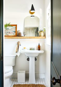 a bathroom with a toilet, sink and mirror on the shelf above it's door