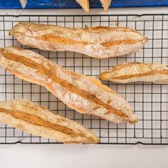 four loaves of bread sitting on top of a cooling rack next to other food items