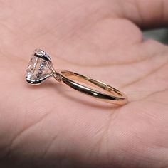 a close up of a person's hand holding a ring with a diamond on it