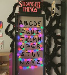 a door decorated with christmas lights and the words strange things written on it in black letters