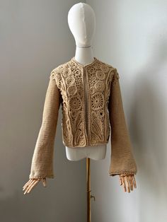 Elevate your wardrobe with this exquisite handmade wool cardigan, intricately crafted using traditional Irish lace techniques. This beige cardigan showcases the timeless elegance of crochet artistry, meticulously designed to offer both comfort and sophistication. Handmade with care, each piece is a unique blend of soft wool and delicate lacework, making it a perfect addition to any outfit. Whether for a special occasion or everyday wear, this cardigan combines classic charm with modern style, en Elegant Fall Crochet Top, Elegant Beige Fitted Crochet Top, Elegant Beige Crochet Top With Crochet Trim, Elegant Fall Lace Crochet Top, Elegant Lace Crochet Top For Fall, Elegant Beige Lace Crochet Top, Fitted Elegant Cardigan With Crochet Lace, Elegant Crochet Lace Cardigan, Fitted Crochet Lace Cardigan For Fall