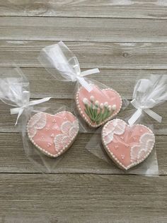 three decorated heart shaped cookies sitting on top of a wooden table