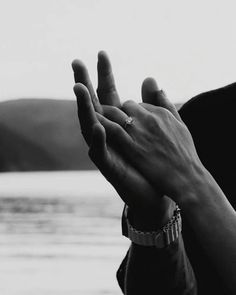 black and white photograph of two hands holding each other with water in the back ground