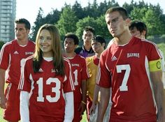 a group of young people standing next to each other on a field with soccer uniforms