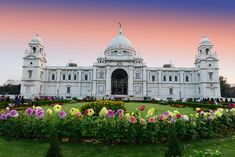 a large white building with many flowers around it