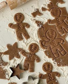 gingerbread cutouts and cookie cutters sitting on a table next to some flour