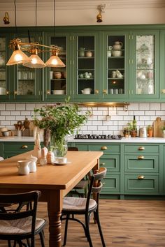 a kitchen filled with lots of green cabinets next to a dining room table and chairs