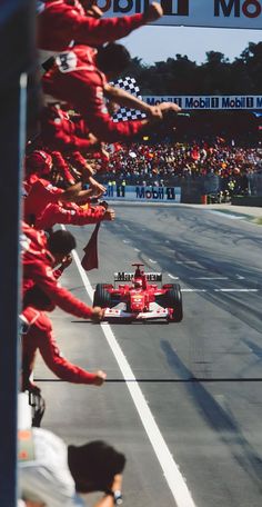 the race cars are lined up on the side of the road as people look on