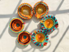 four orange and blue dishes sitting on top of a white table