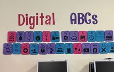 two computer monitors sitting next to each other in front of a sign that says digital abc's