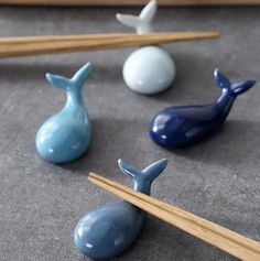 three blue whale shaped chopsticks are on the table next to some white balls