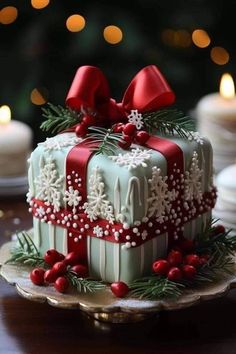 a christmas cake decorated with red bows and snowflakes on a table next to candles