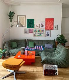 a living room with green couches and pictures on the wall above it's coffee table