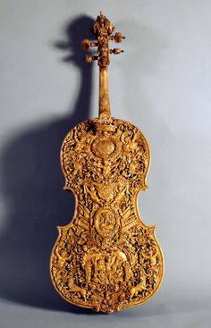 an old violin with ornate carvings on the front and back sides, against a gray background