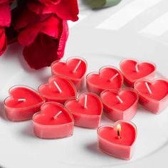 heart shaped candles are on a plate next to flowers