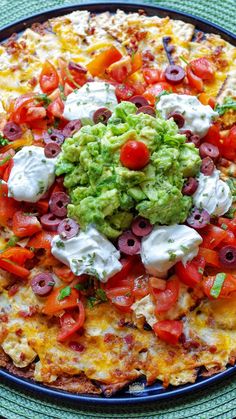 a pizza topped with guacamole and tomatoes on top of a blue plate