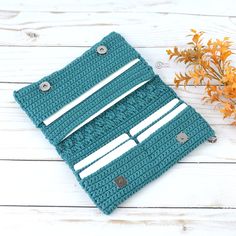 a blue crocheted purse sitting on top of a white wooden table next to an orange flower