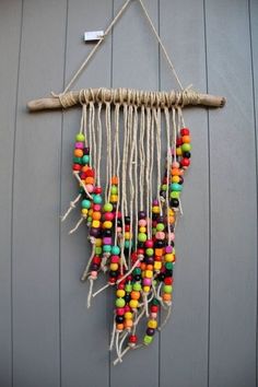 a multicolored beaded dream catcher hangs on a gray wall