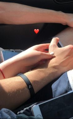 two people sitting in the back seat of a car with their hands on each other's wrist