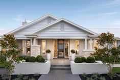 a white house with two large planters in front of the door and entry way