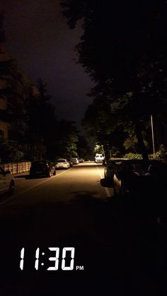 a dark street with cars parked on both sides and the word time written in white