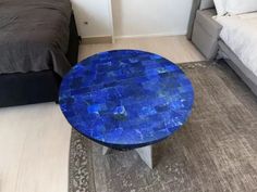 a blue table sitting on top of a rug next to a bed