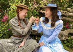 two women dressed in period clothing are sitting on a bench and one is touching the other's hand