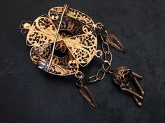 "This handsome, flickering brooch features detailed filigree and cannetille work. The brooch is quite dimensional with raised and dangling ornament. It was probably made in Portugal or Spain. The security clasp works just fine. The brooch is in good shape with some surface wear to the gilding. It is 6.7cm (2 5/8\")long X 3.2cm (1 1/4\")wide. It weighs 10g." Ornate Filigree Jewelry For Evening, Ornate Gold Locket Brooches, Antique Pendant Brooch With Intricate Design, Antique Brooch With Intricate Pendant Design, Antique Yellow Gold Filigree Brooches, Victorian Gold Brooches With Intricate Design, Victorian Gold Brooch With Intricate Design, Gold Victorian Brooches With Intricate Design, Gold Victorian Brooch With Intricate Design