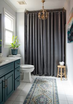 a bathroom with blue cabinets and a rug on the floor in front of the shower