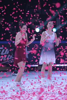 two women in short dresses standing next to each other with confetti falling around them