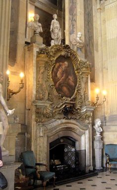 an ornate fireplace in the middle of a room with statues on either side of it